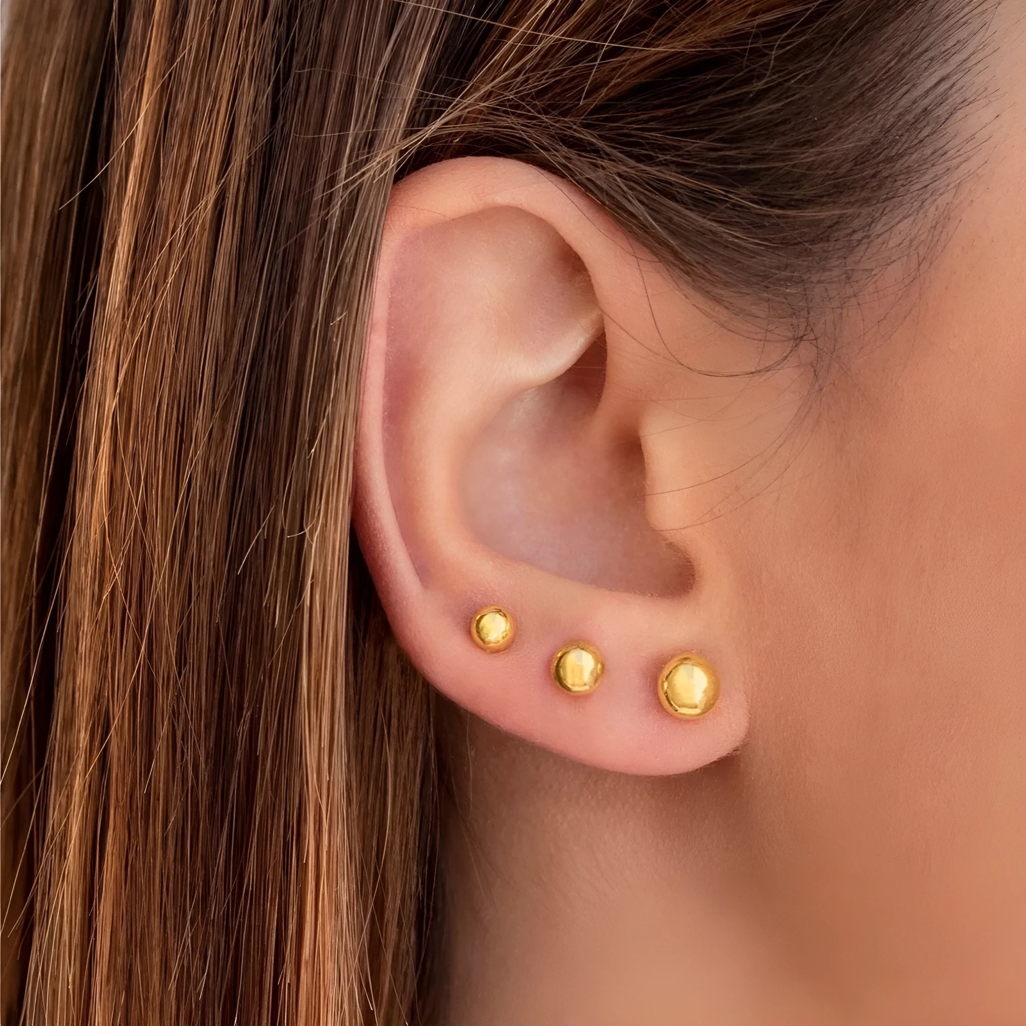 Minimalist round ball stud earrings in gold and silver plating on a white background.
