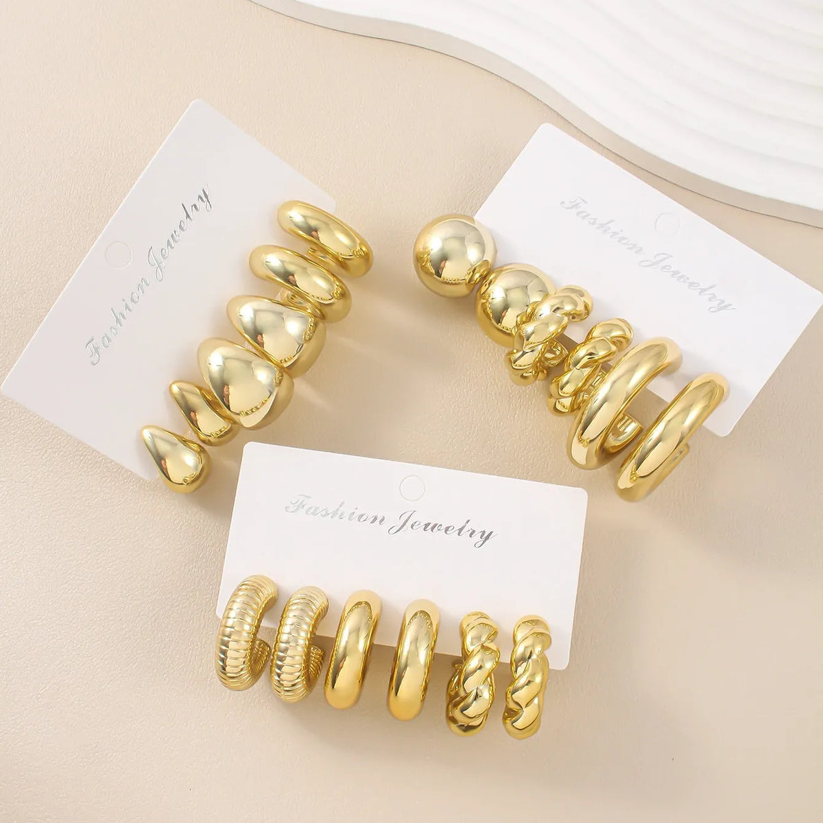 Set of three pairs of acrylic double circle earrings in gold, silver, and black with water drop design