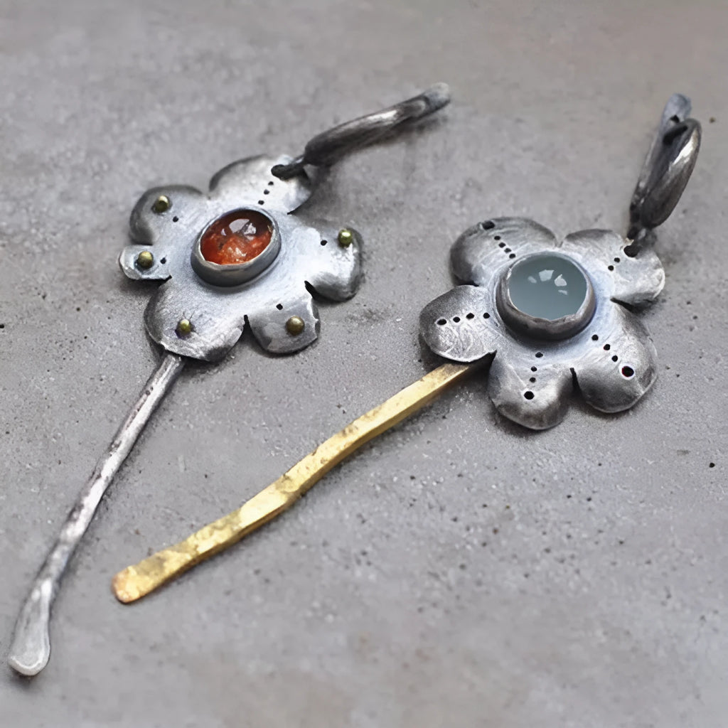 A pair of long, geometric flower-shaped drop earrings with an asymmetric two-tone metallic finish.