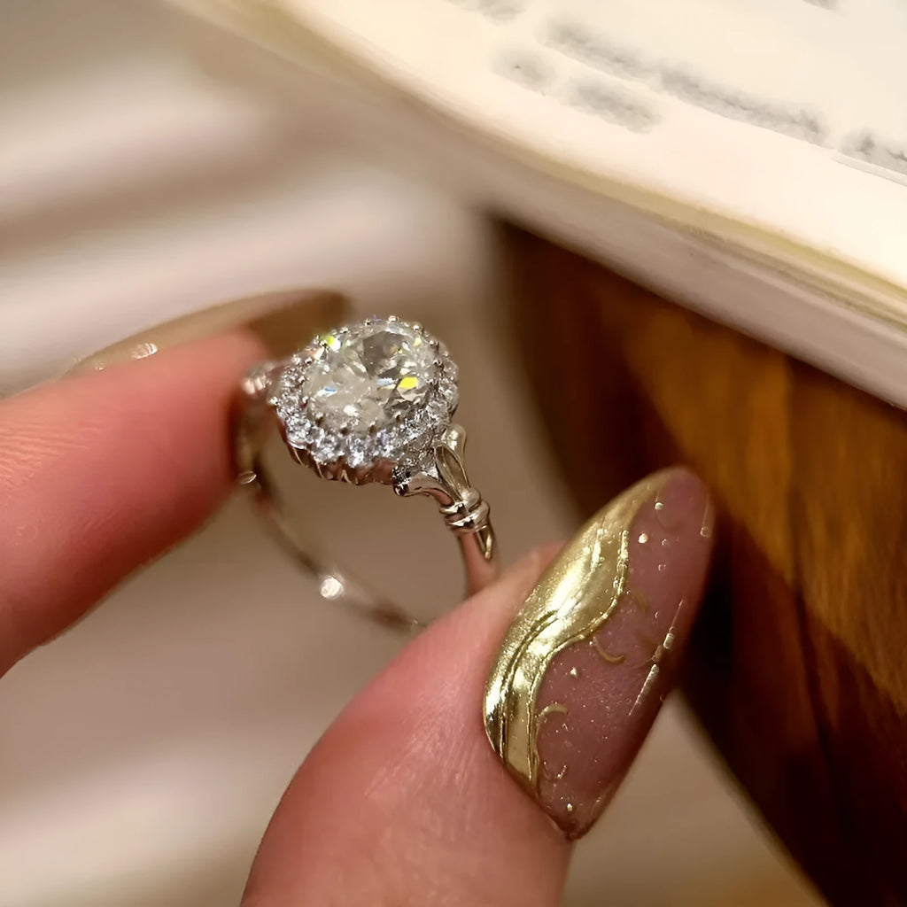 Silver geometric ring with an elliptical diamond centre on a model's hand, showing adjustable opening.
