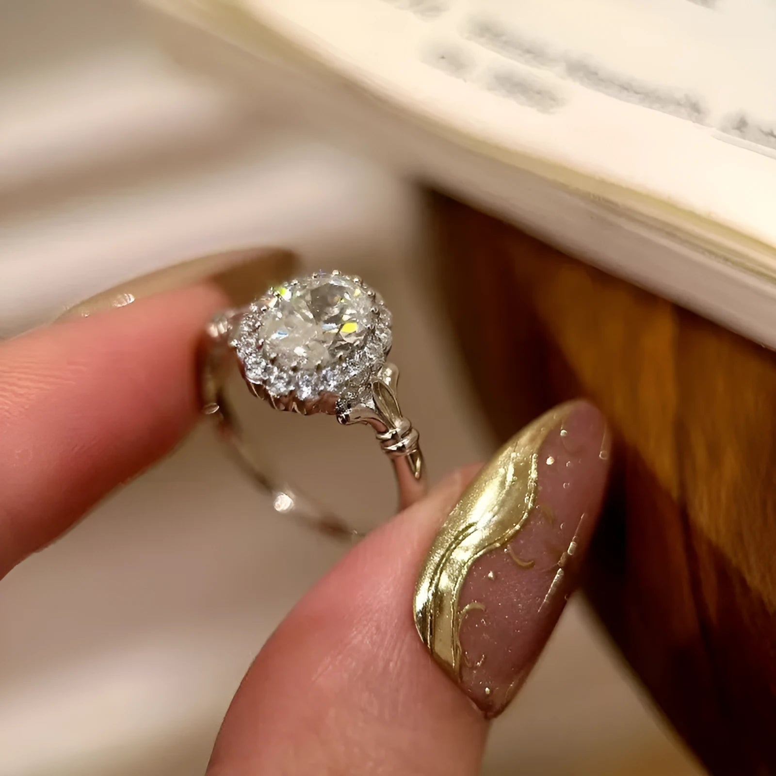Silver geometric ring with an elliptical diamond centre on a model's hand, showing adjustable opening.