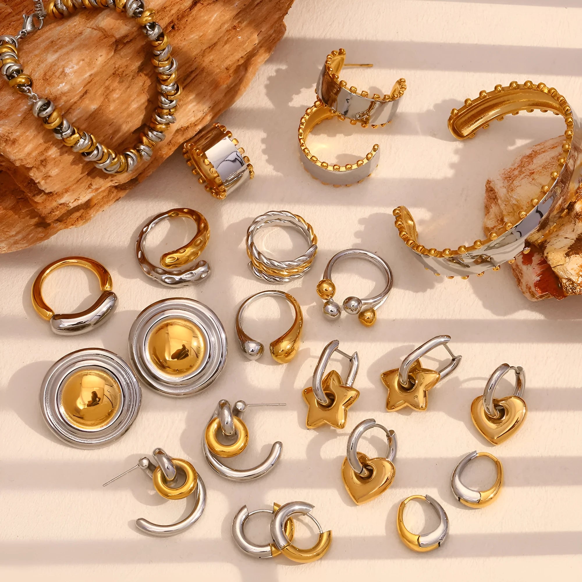 Geometric gold-tone stainless steel jewellery set showing earrings, a bracelet, and a necklace with circular designs on a grey background.