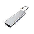 Grey aluminium USB-C docking station with HDMI, VGA, USB 3.0, and PD charge ports on a wooden desk.