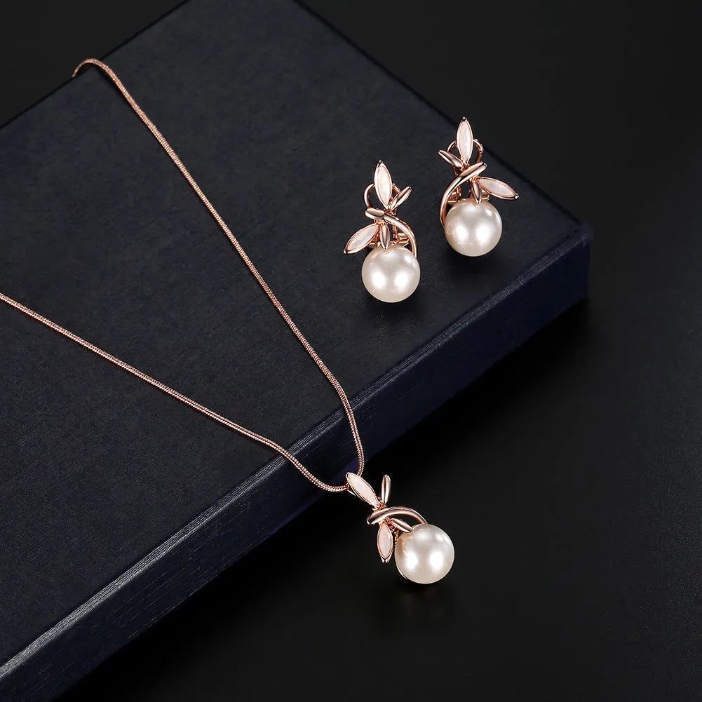 Rose gold alloy necklace with artificial gem pendant and matching earrings on a display surface