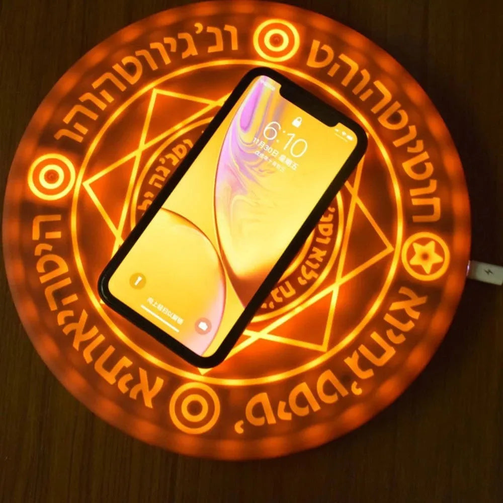 Square black wireless charging pad with glowing magic array pattern, charging a mobile phone.