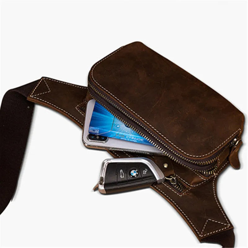 Brown top-layer cowhide men's sports waist bag shown with a 10-inch laptop and phone next to it for scale.