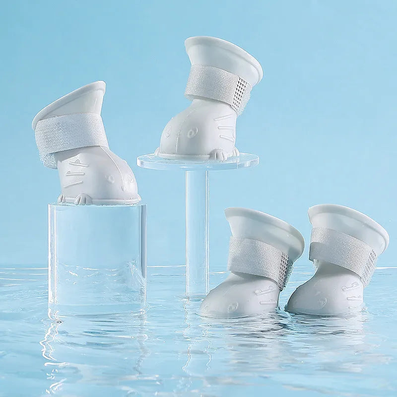 Four waterproof silicone dog rain boots in blue, grey, light blue and pink on a white background