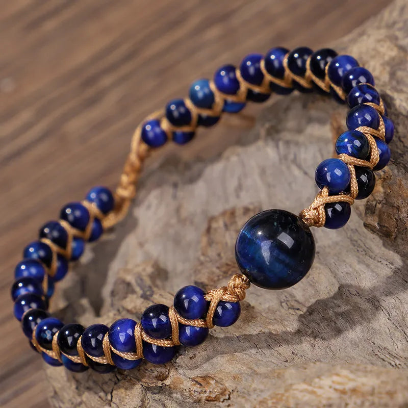 Close-up of a handmade woven bracelet featuring blue tigereye beads in a geometric pattern on a wrist.