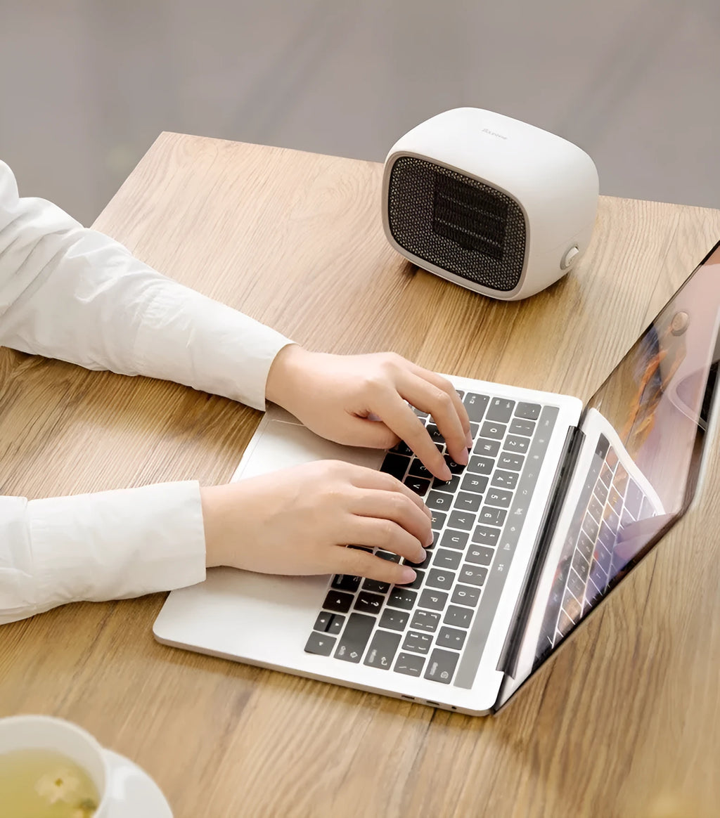 Compact green mini desktop heater with metal grille and EU plug on a wooden desk.