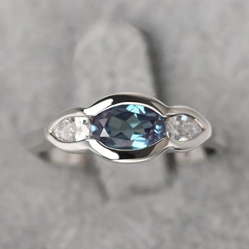 A geometric ellipse-shaped ring with an inlaid zircon, in a white gold colour finish.