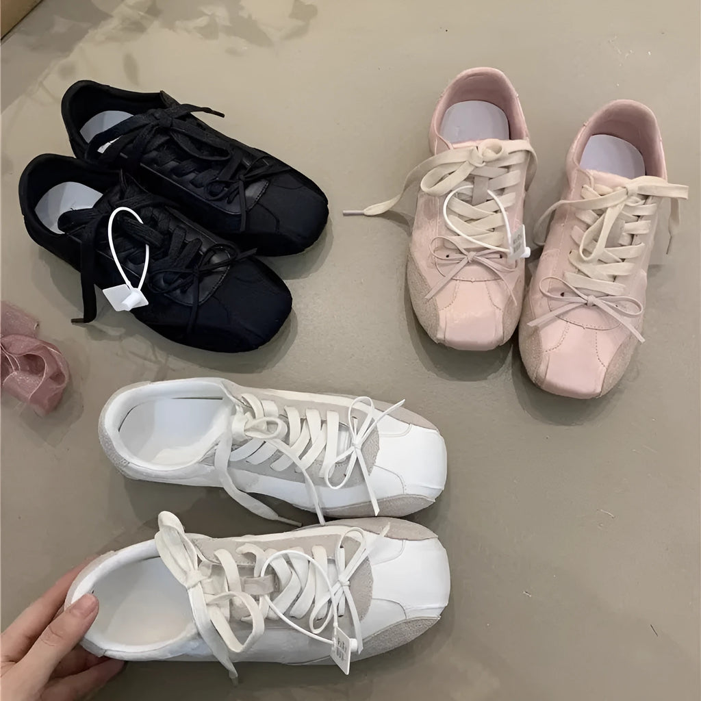 Women's low-top white sneaker with bow detail, microfiber upper, round toe, lace-up closure