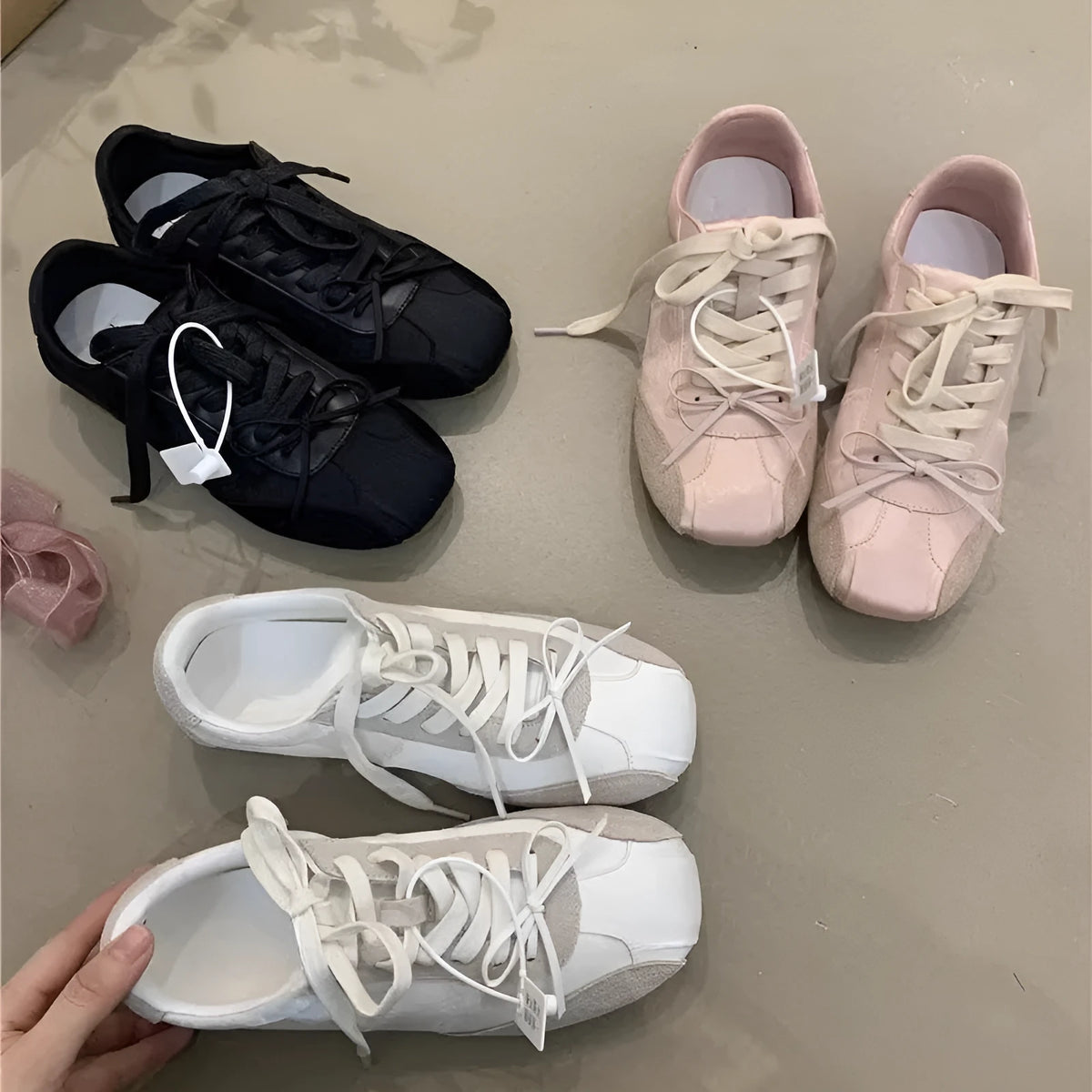 Women's low-top white sneaker with bow detail, microfiber upper, round toe, lace-up closure