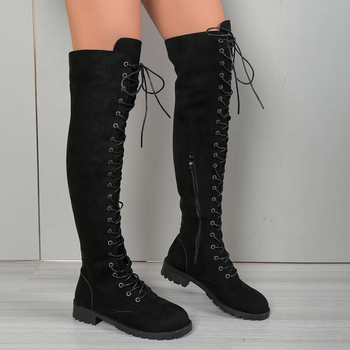 Black lace-up over-the-knee boots with a round toe, flat rubber sole, and decorative stitching on the shaft.