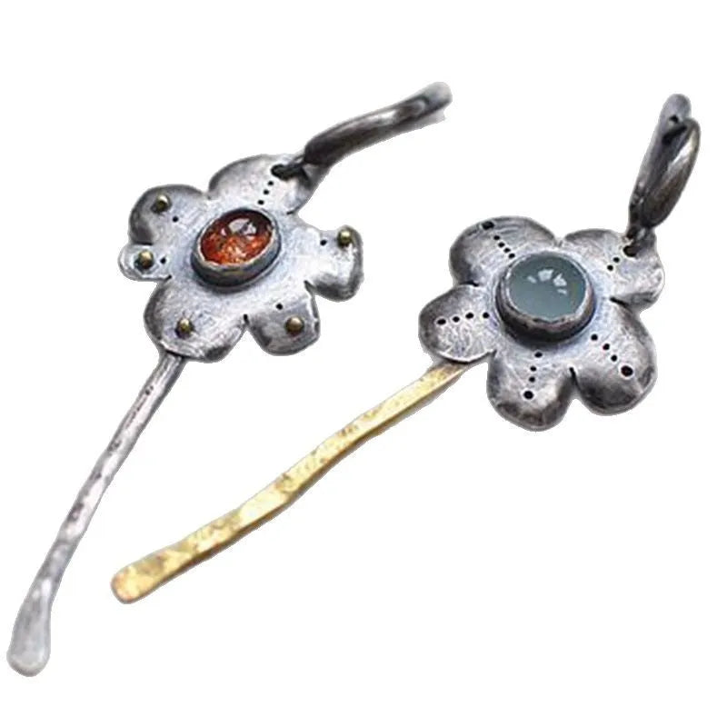 A pair of long, geometric flower-shaped drop earrings with an asymmetric two-tone metallic finish.