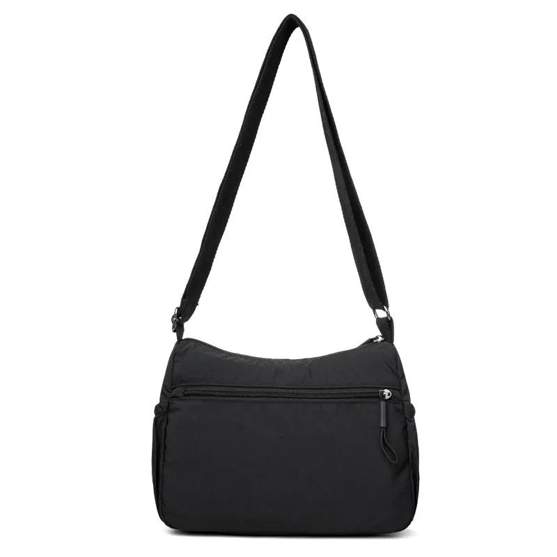 Soft water-repellent nylon crossbody bag with a three-dimensional front pocket and adjustable strap.