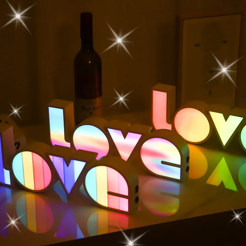 LED LOVE light with rainbow-coloured plastic lampshade on a desk