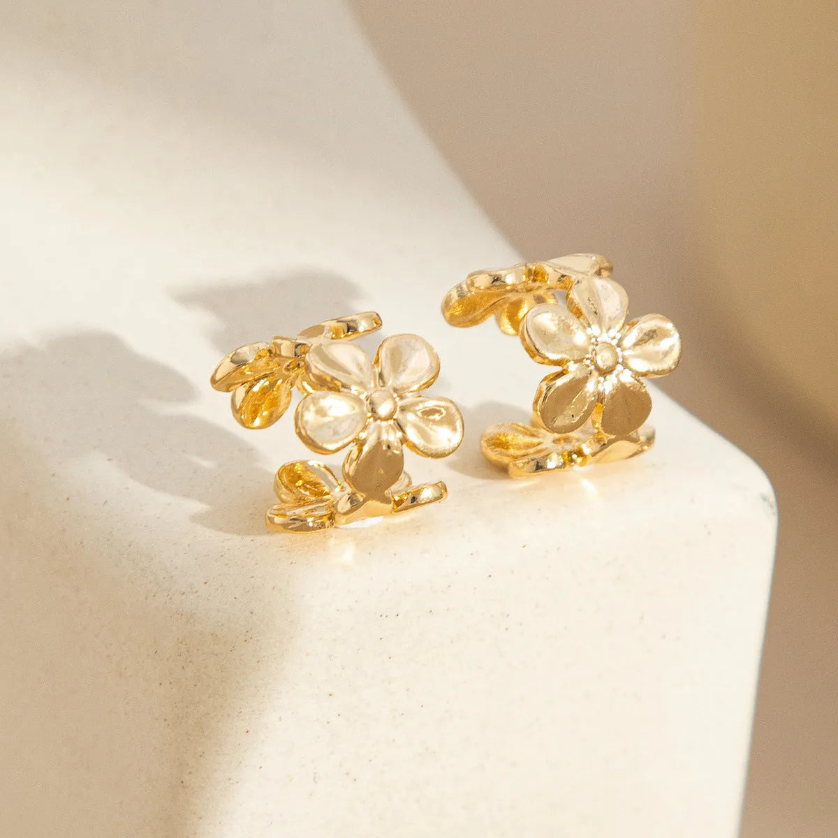 Gold-coloured alloy earrings with starfish and conch designs on a white background.