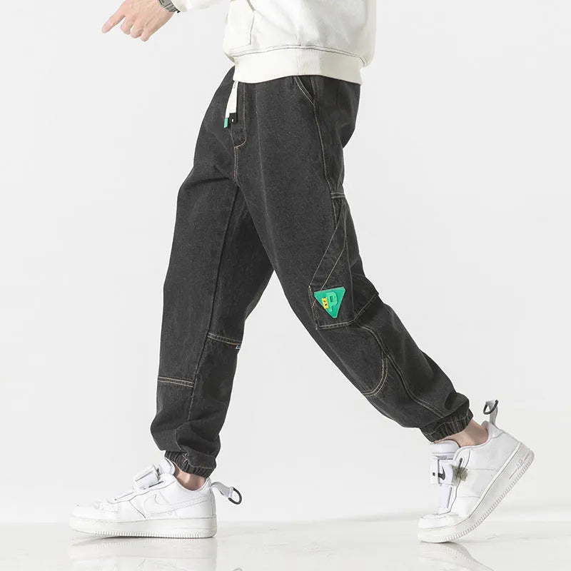 Men's loose-fit tapered cotton trousers in grey, shown on a model, featuring a mid-waist and tapered leg.