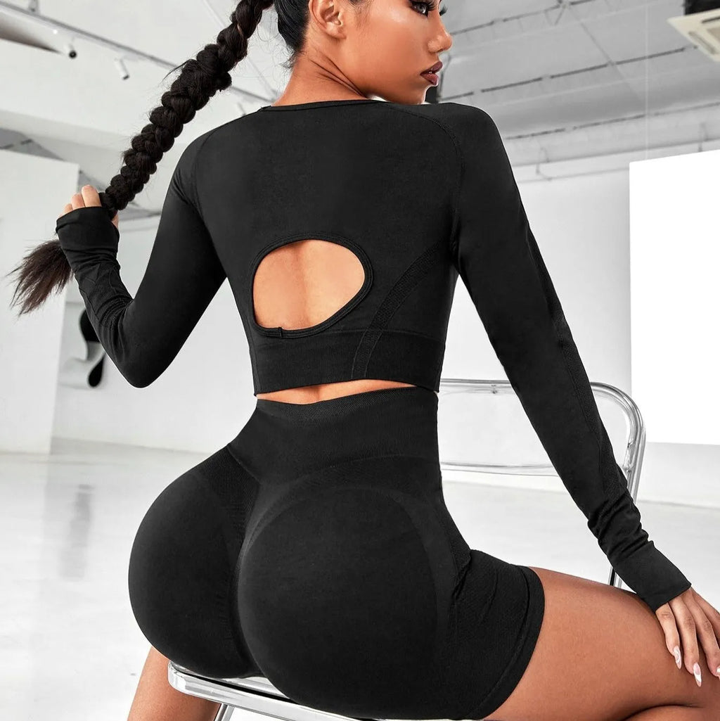 Women's black high-waist yoga pants and long-sleeve top set laid flat.