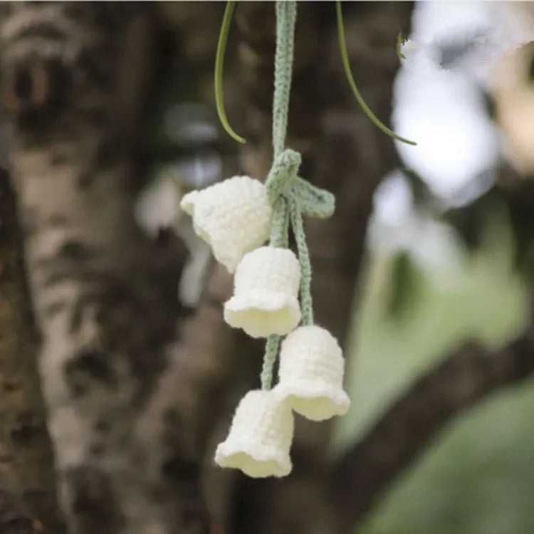 Green and white knitted wool car plant decoration with small basin and hanging rope.