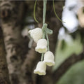 Green and white knitted wool car plant decoration with small basin and hanging rope.