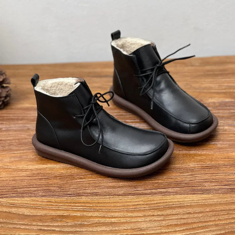 Women's black cowhide winter boots with flat heel and round toe on neutral background