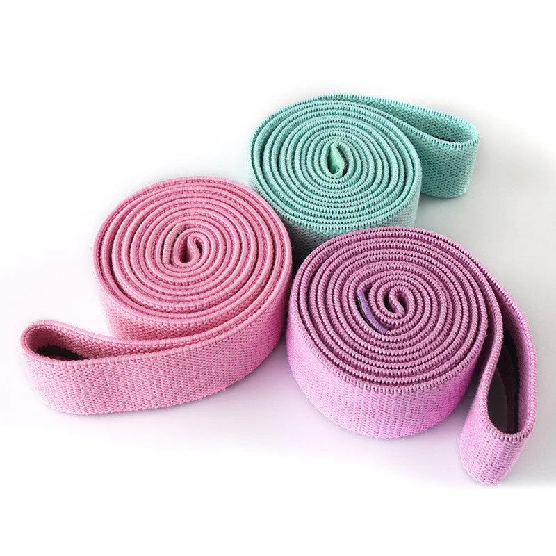 Three polyester cotton and latex silk resistance bands 200 x 4 cm in blue pink and purple on a flat surface