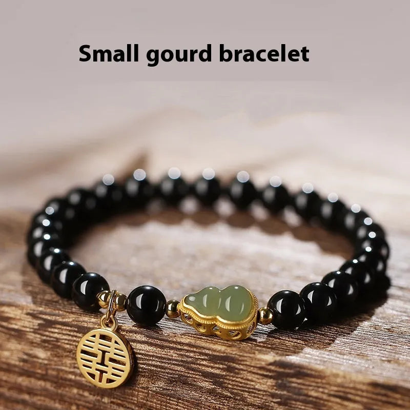 Black obsidian bead bracelet with a carved Hetian jade gourd charm in geometric pattern.