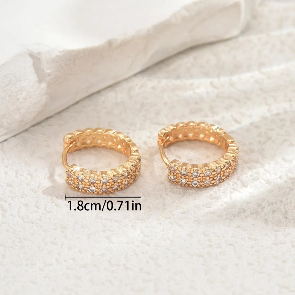 A pair of copper geometric ear studs featuring a round ring with a central dot, on a grey background.