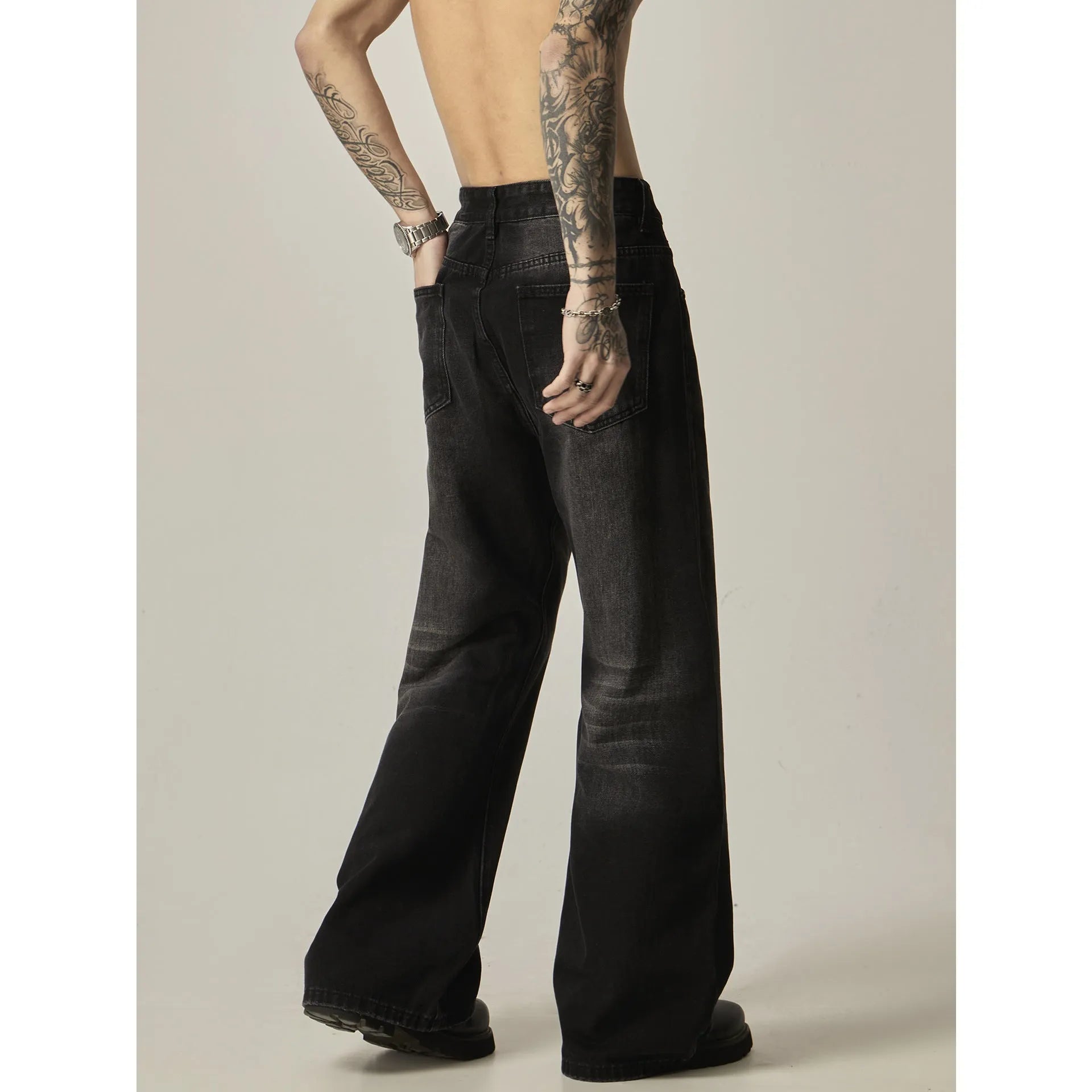 Black loose-fit straight leg denim jeans with a zipper fly on a neutral background.