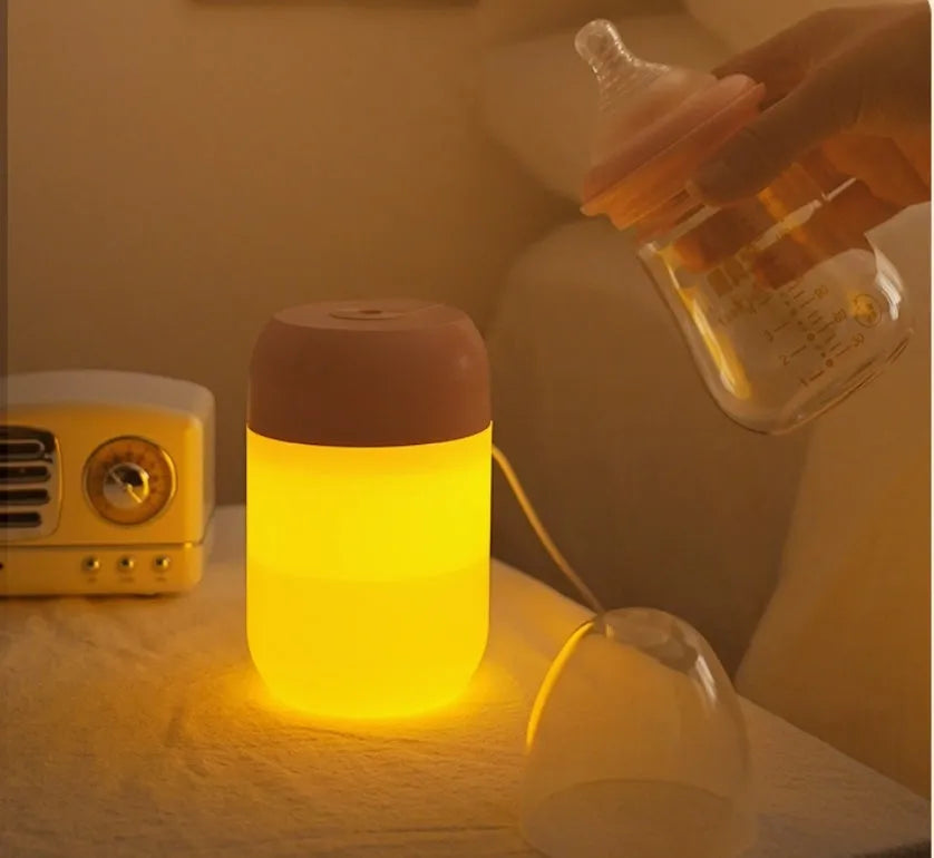 White cylindrical mini USB humidifier on a wooden desk next to a laptop.