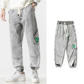 Men's loose-fit tapered cotton trousers in grey, shown on a model, featuring a mid-waist and tapered leg.