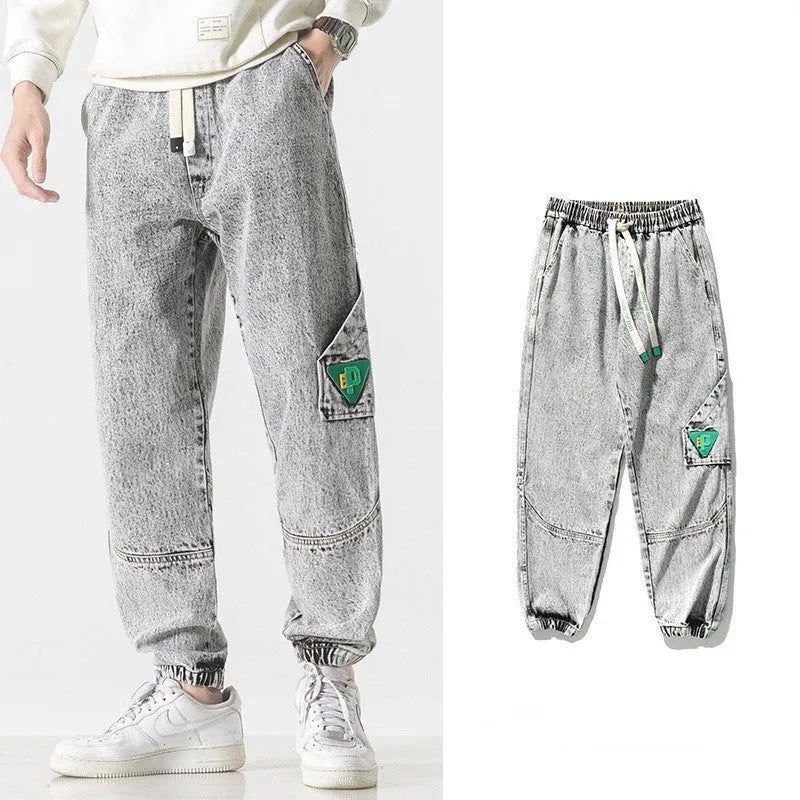 Men's loose-fit tapered cotton trousers in grey, shown on a model, featuring a mid-waist and tapered leg.