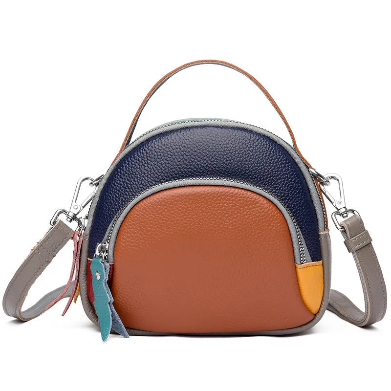 Round hand-held crossbody bag made from first layer cowhide leather with visible sewing line detail on exterior