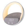 Beige multifunctional wireless charging Bluetooth speaker with clock and adjustable LED mood lighting on a wooden table.