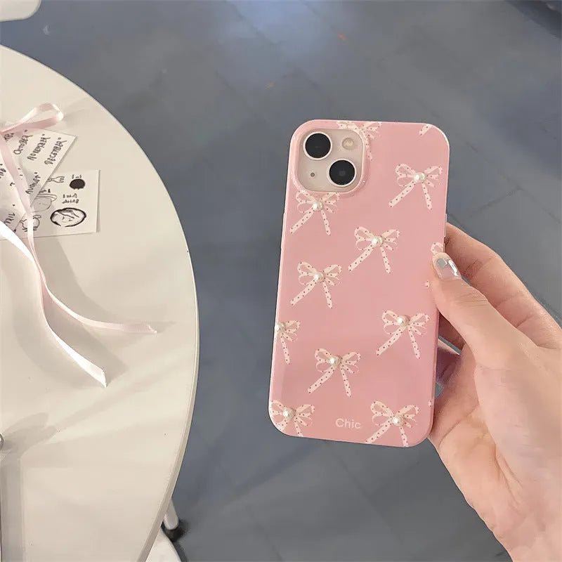 Pink soft TPU iPhone case with three-dimensional pearl dot bow, compatible with iPhone 11 to 15 Pro Max.