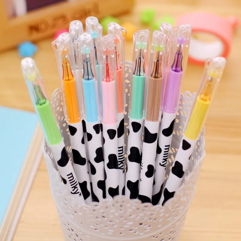 Set of 12 cow print design gel pens with 0.38mm tips in assorted colours laid out next to their box.