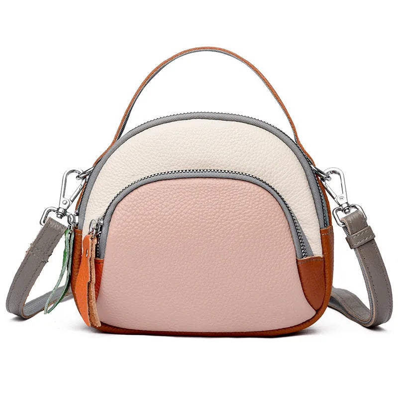 Round hand-held crossbody bag made from first layer cowhide leather with visible sewing line detail on exterior