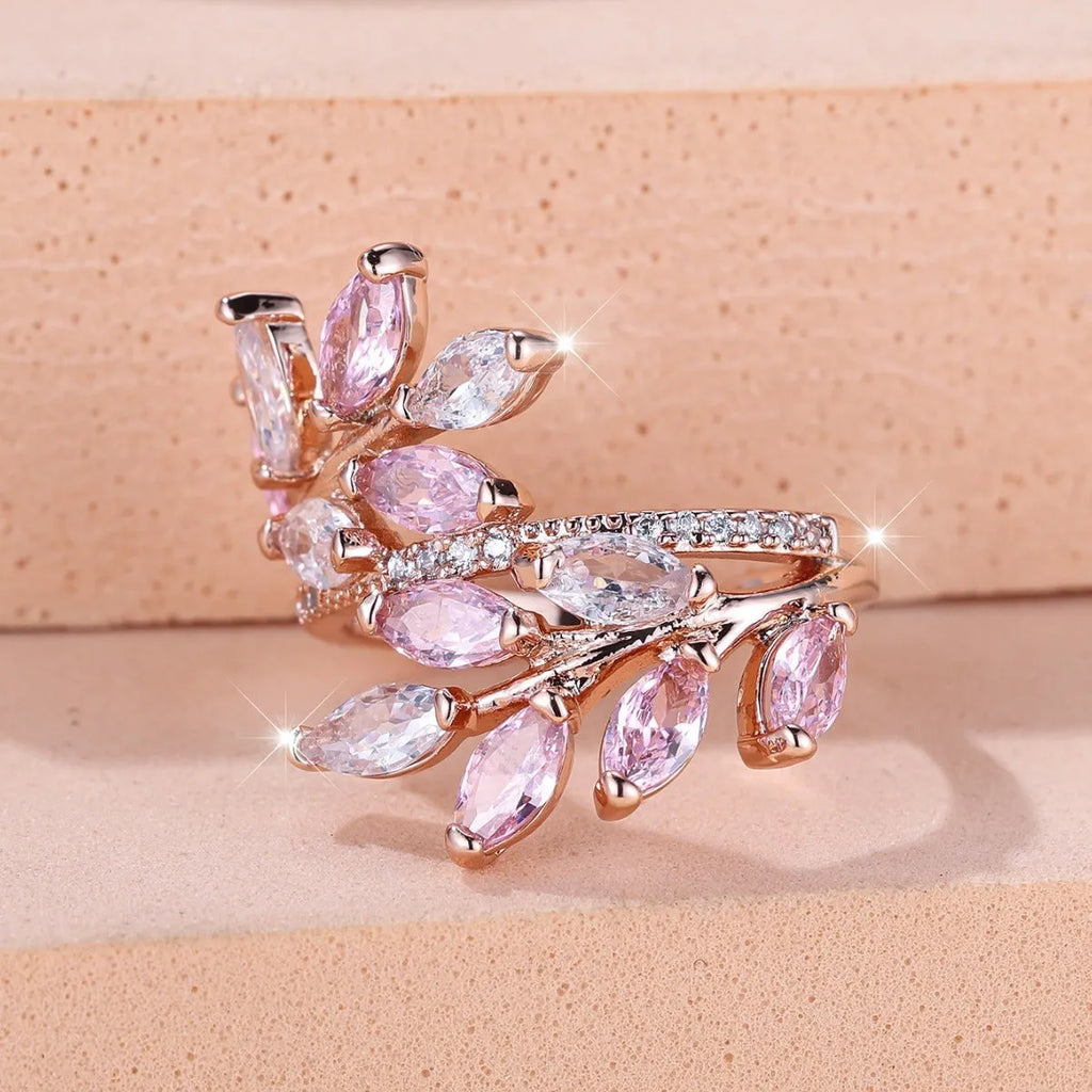Adjustable open-ended copper ring with leaf design and central blue zircon stone on a finger.