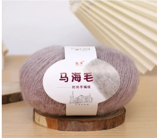 A ball of mohair yarn in a selected colour next to a hand-woven scarf example, showcasing the DIY kit.