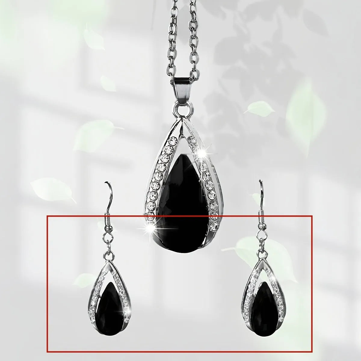 Black and red teardrop-shaped glass pendant necklace and matching stud earrings set on a grey background.