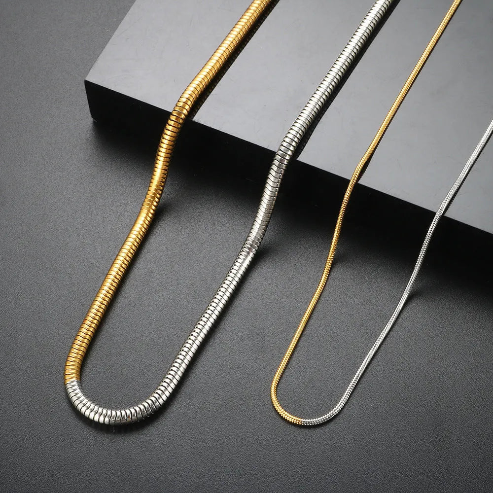 Gold-coloured snake bone chain necklace with geometric links on a white background.