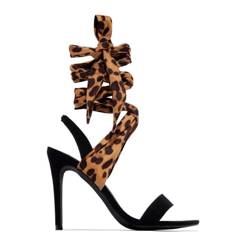 Light brown leopard print women's high heel sandals with cross straps and a thin stiletto heel on a white background.