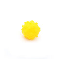 Bright blue, green, pink and yellow spiked squeaky dog balls for small breeds on a grass background.