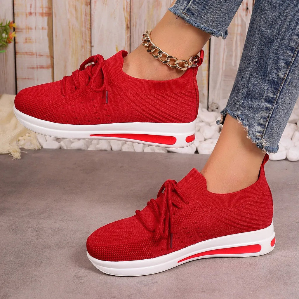 Women's low-top casual sneakers in red with front lace-up and round toe on a plain background.