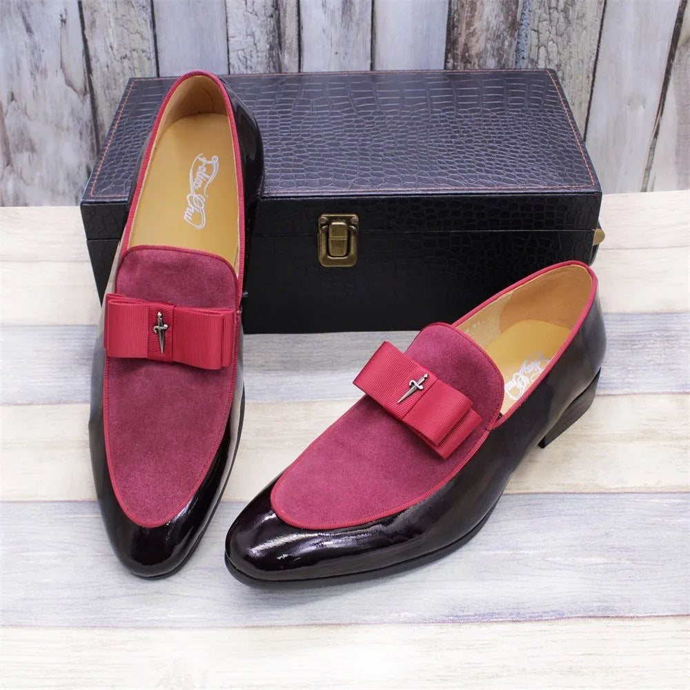 Men's black tassel loafers with glossy patent leather upper and matte leather toe holder on a wooden floor.