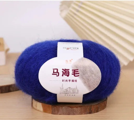 A ball of mohair yarn in a selected colour next to a hand-woven scarf example, showcasing the DIY kit.