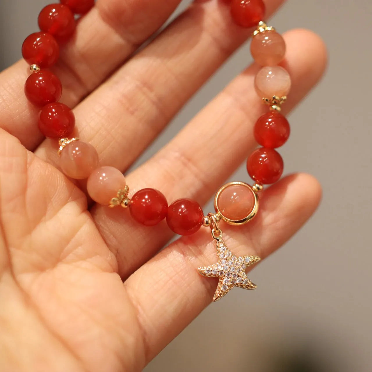 Handmade red agate bracelet with 8mm beads, star and xiangyun patterns, on a wrist.