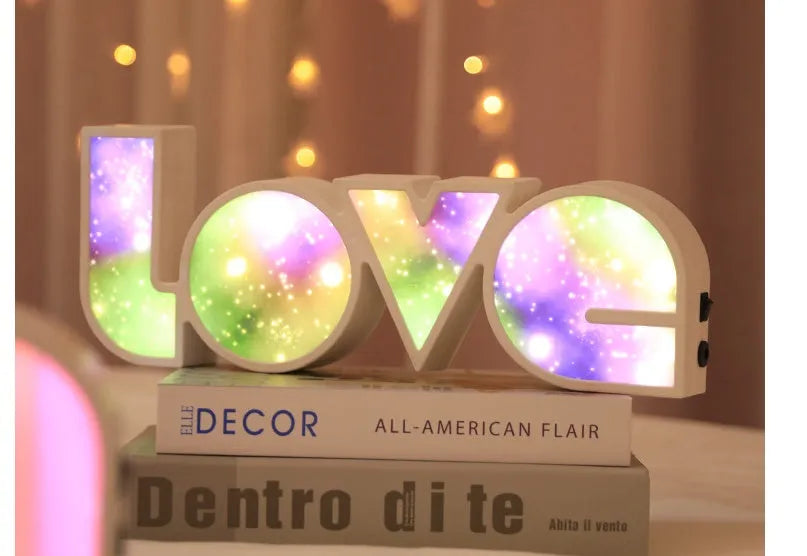 LED LOVE light with rainbow-coloured plastic lampshade on a desk
