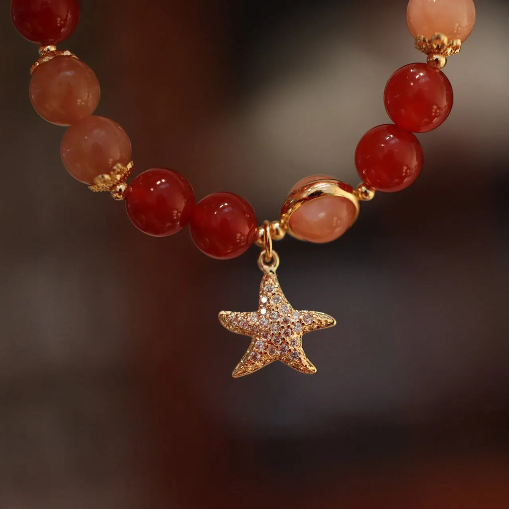 Handmade red agate bracelet with 8mm beads, star and xiangyun patterns, on a wrist.